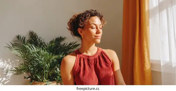 Young woman with curly hair sitting by window in bright room
