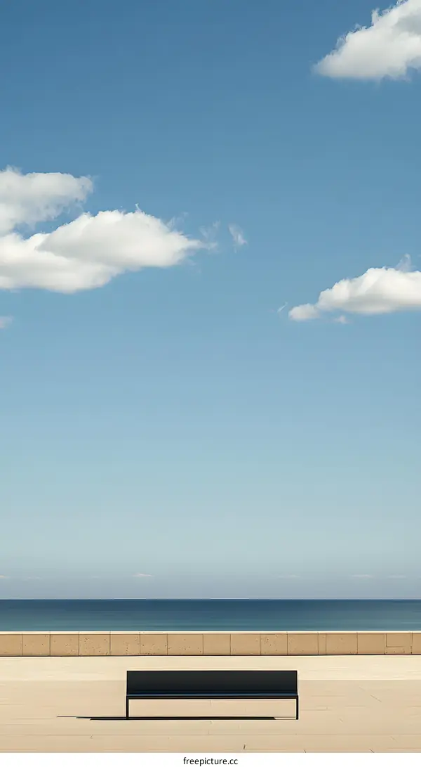 Single Bench Facing the Ocean Under a Blue Sky