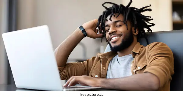 Smiling Man With Dreadlocks Using Laptop
