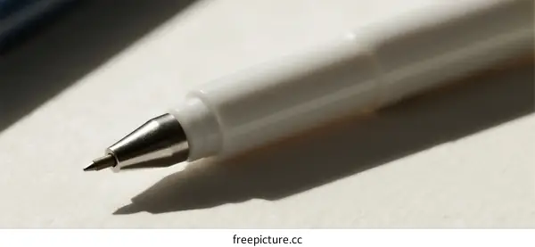 Close-up view of a white ballpoint pen on a light surface