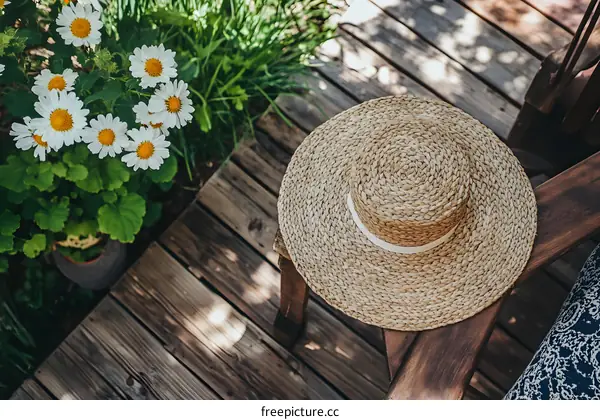 Straw Hat on Wooden Patio with Daisies