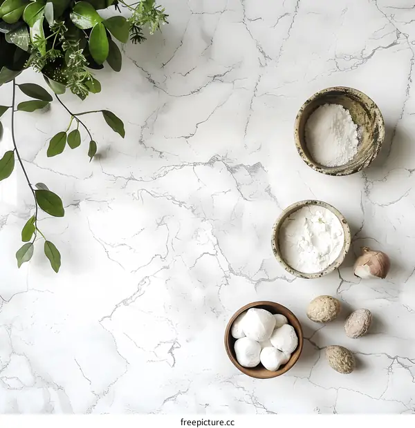 White Marble Background with Green Greenery and Bowls of White Powder