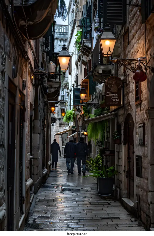 Narrow Cobblestone Street in European City with Three People Walking