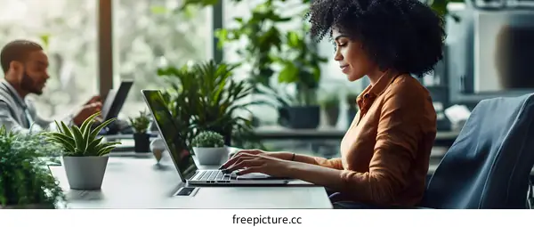 African American Woman Working on Laptop in Modern Office with Plants