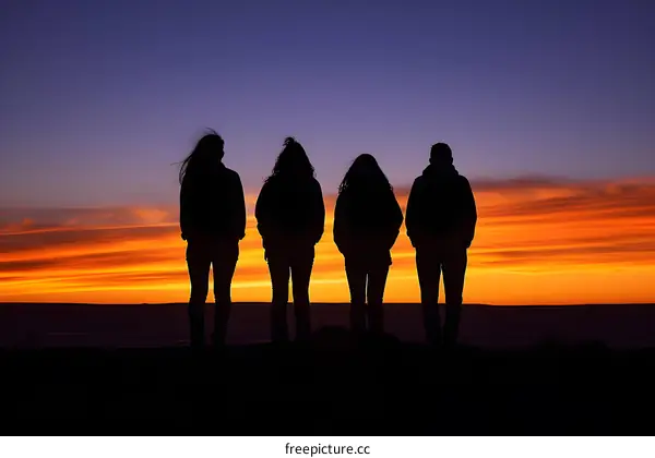 Silhouettes of Four People Standing in Front of a Sunset