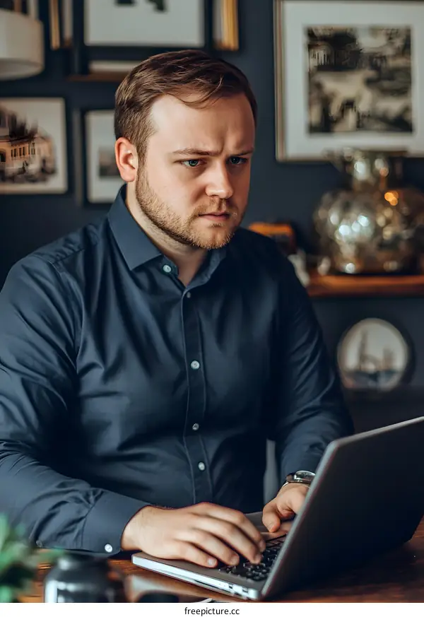 Serious Caucasian Man Working on Laptop Computer at Home Office