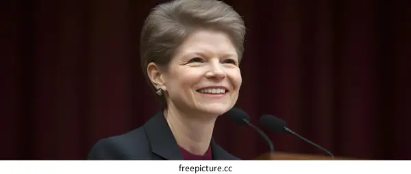Smiling Woman Speaking at a Podium with Microphones