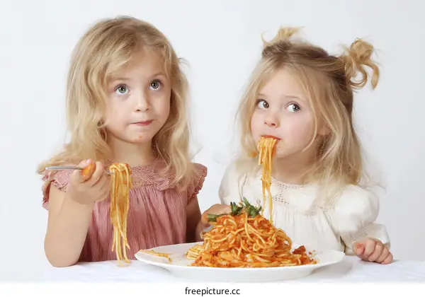 Two Caucasian Children Eating Spaghetti