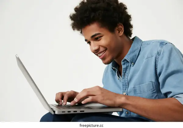 Young man using a laptop with a focused expression