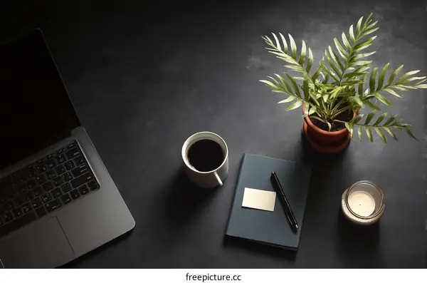 Dark Workspace with Laptop, Coffee, Plant and Notebook