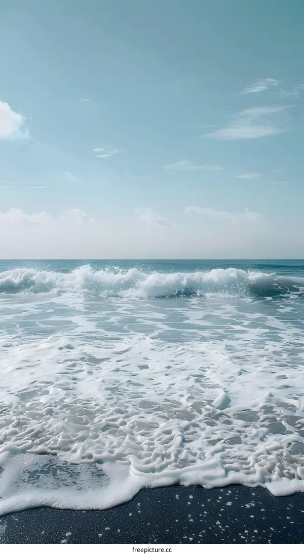 Ocean Waves Crashing On Sandy Beach Under Blue Sky