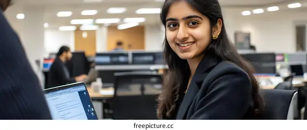 Smiling Young Woman Working on Laptop in Office