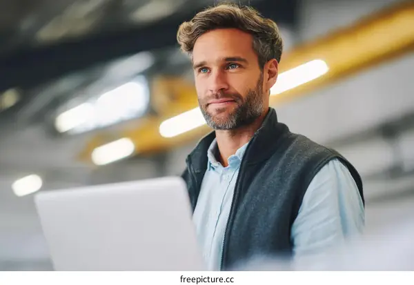 Caucasian Man Working on a Laptop in a Factory