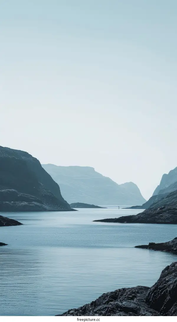 A boat sails through a narrow fjord between tall mountains