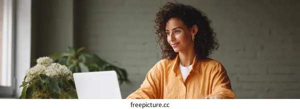 A woman working on laptop with green plant in modern office
