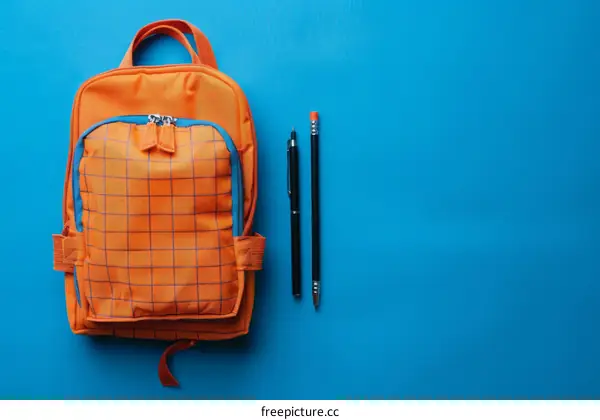 Orange backpack and blue stationary on blue background