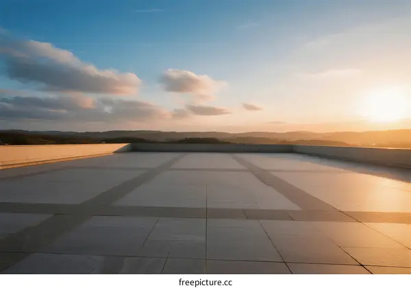 Sunset view from a spacious rooftop with clear sky and distant hills