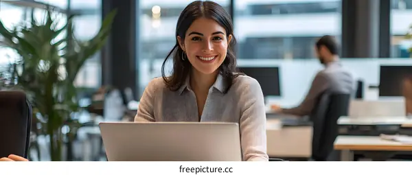 Smiling Woman Working on Laptop in Modern Office
