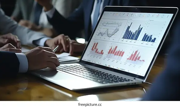 Business people analyzing financial data and graphs on laptop screen during meeting
