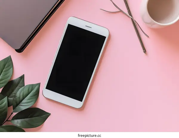 Flat Lay of White Phone and Green Leaves on Pink Background