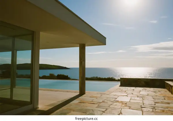 Modern house with pool overlooking the sea under sunny sky