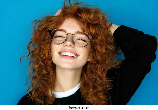 Smiling Redhead Woman in Glasses against a Blue Background
