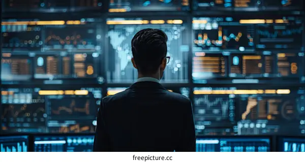 Businessman looking at multiple monitors with graphs and charts