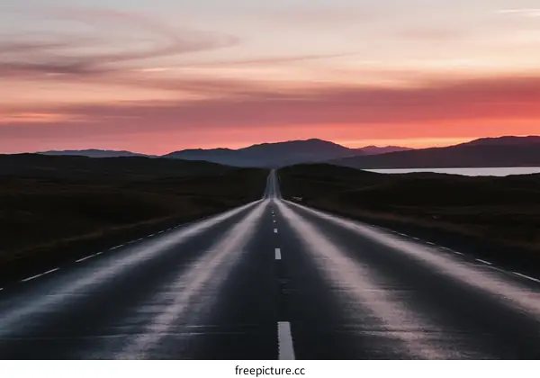 A Long Road Stretching into the Distance Under a Colorful Sunset Sky