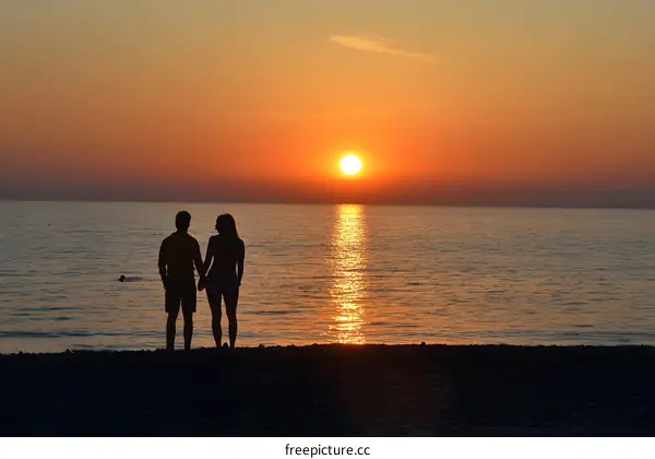 Couple Silhouettes Watching Sunset Over Ocean