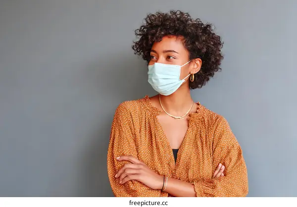 Woman Wearing Mask in Front of a Gray Wall