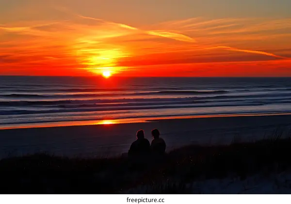 Silhouettes of Couple Watching Sunset Over Ocean