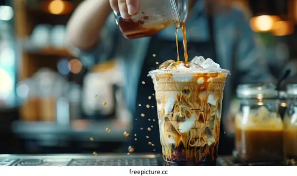 Barista pouring milk into iced coffee
