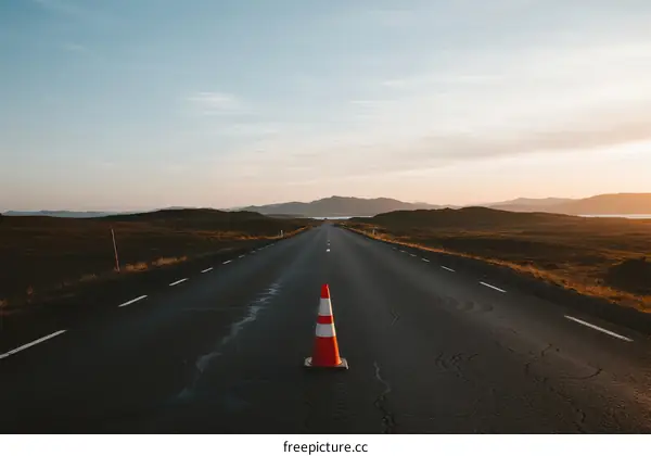 Empty road with traffic cone under clear sky during sunset