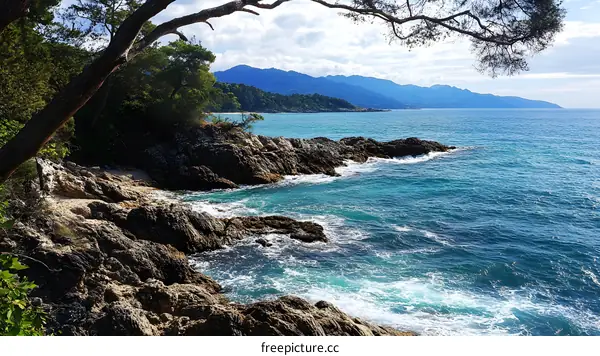 Rocky Coastline with Blue Water and Distant Mountains