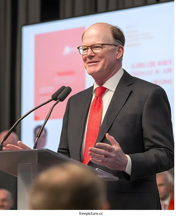 Man in Suit Speaking at Podium with Microphone
