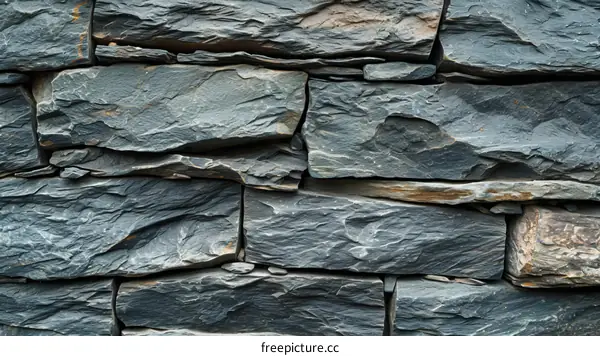 Rough dark grey slate stone wall texture background