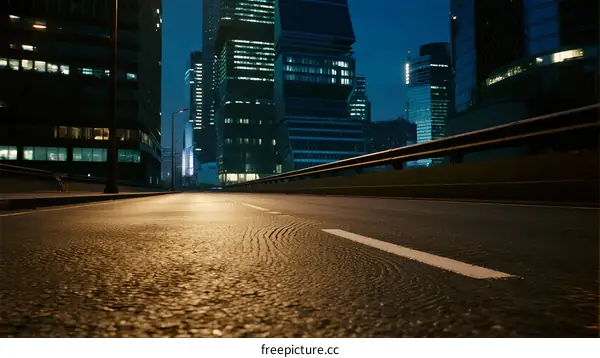 City road at night with modern tall buildings in the background
