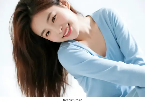 A young woman with long hair wearing a light blue top smiling