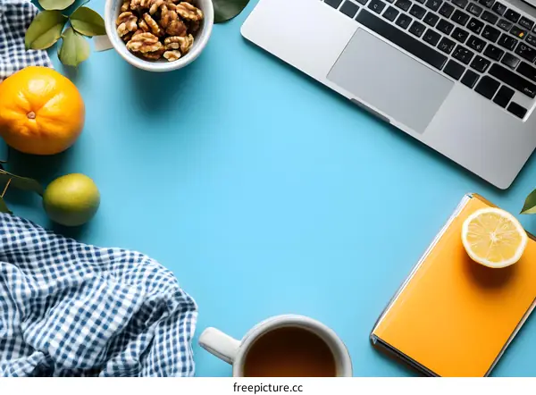 Flat Lay of Workspace with Laptop, Coffee Cup, Nuts, Lemon and Orange