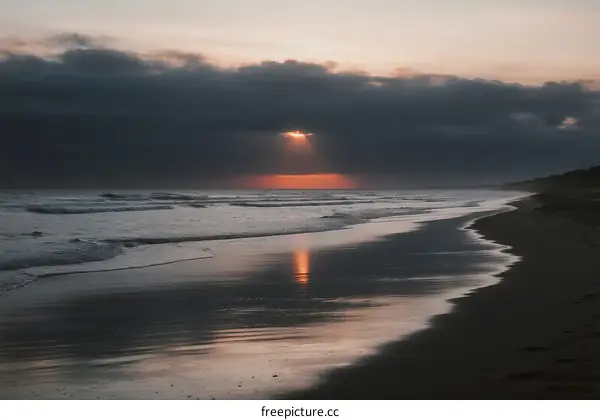 Sunset over the calm ocean with waves and clouds