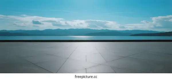 A vast open area with a view of a calm body of water and distant mountains