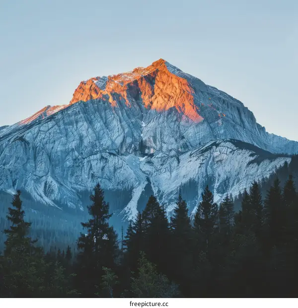 The sun sets behind a snow-capped mountain peak