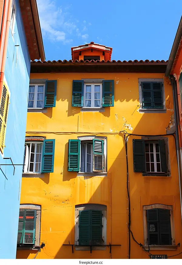 Yellow Building with Green Shutters and a Blue Wall