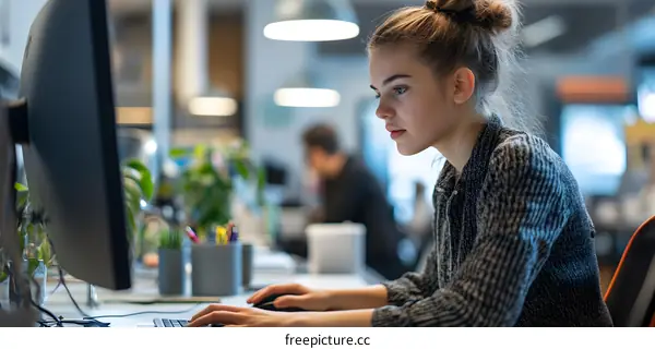 Young Woman Working on Computer at Desk in Modern Office