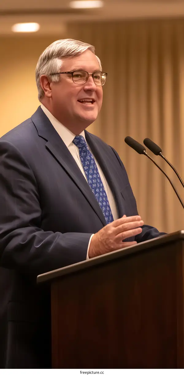 Man in Suit Speaking at a Podium with Microphones
