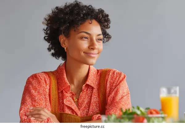 Smiling Woman in Orange Blouse at a Table