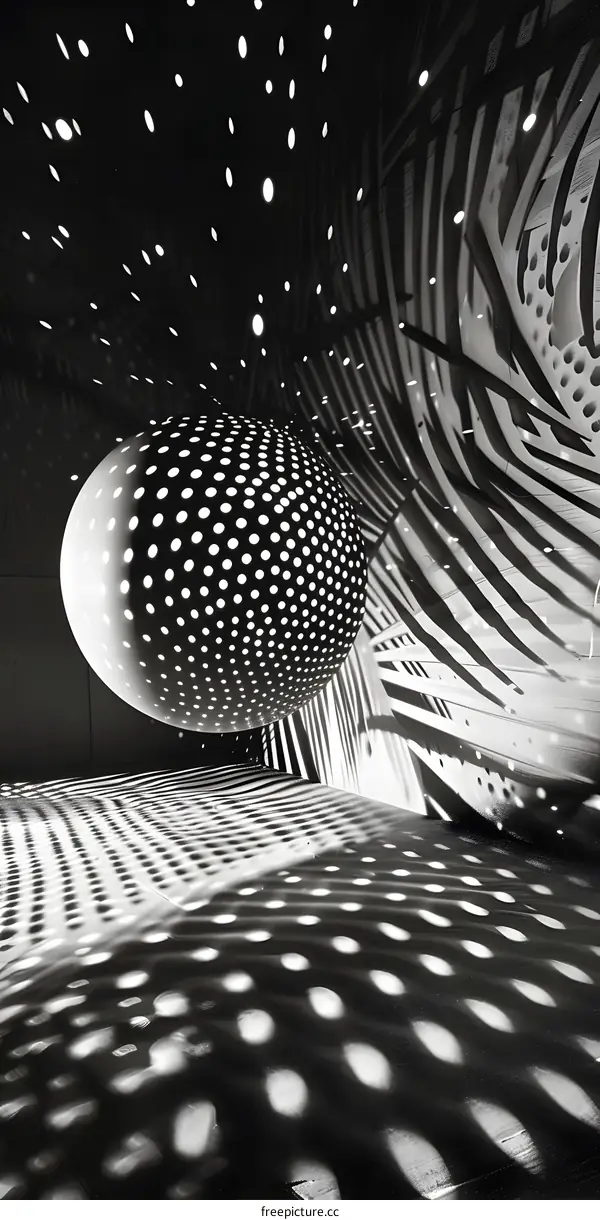 Black and White Photo of a Sphere with Dotted Pattern and Its Shadow