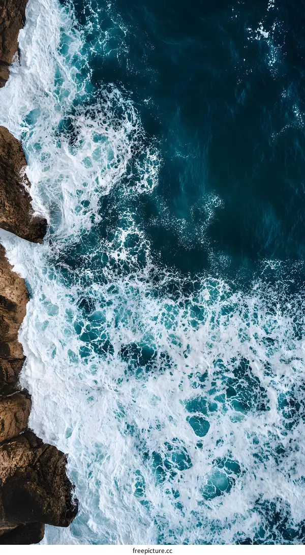 Aerial View of Ocean Waves Crashing Against Rocky Coastline