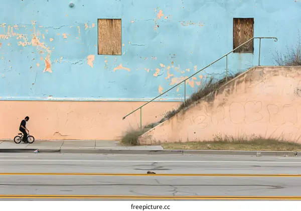 A Person Riding a Bicycle on a Street in Front of a Building