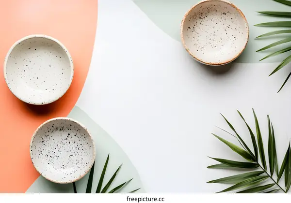 White Ceramic Bowls with Green Palm Leaves on Abstract Background